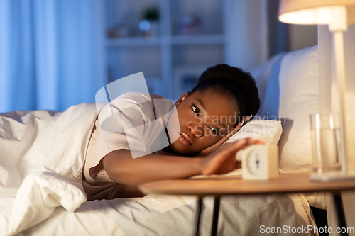 Image of woman awaking because of alarm clock at night