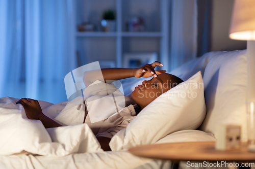 Image of sleepless african woman lying in bed at night