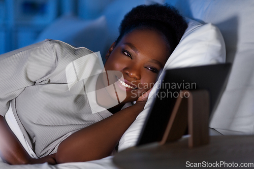 Image of woman with tablet pc in bed at home at night