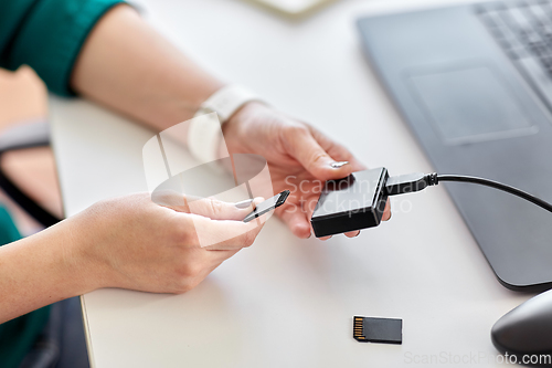 Image of woman with sd card reader and laptop at office