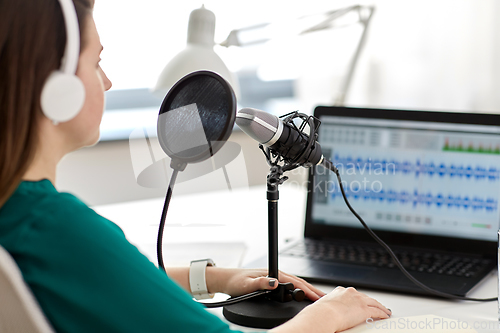 Image of woman with microphone recording podcast at studio