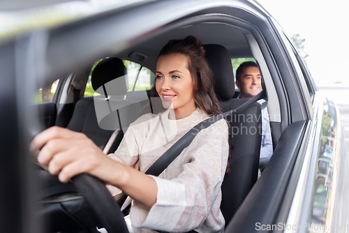 Image of female driver driving car with male passenger