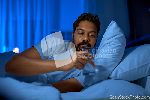 Image of indian man drinking water in bed at night