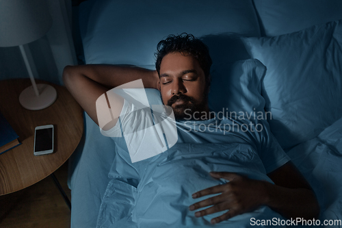 Image of indian man sleeping in bed at home at night