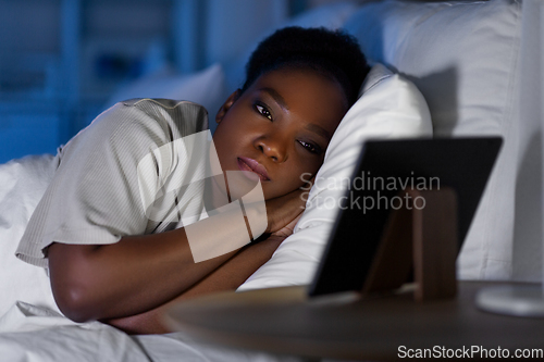 Image of woman with tablet pc in bed at home at night