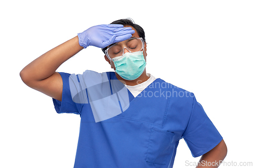 Image of tired indian male doctor in blue uniform and mask