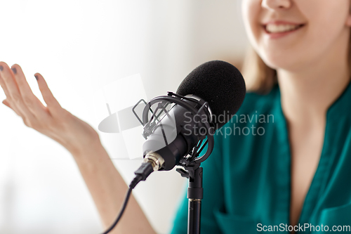 Image of woman with microphone recording podcast at studio