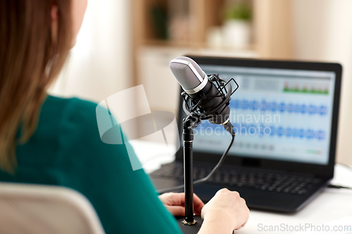 Image of woman with microphone recording podcast at studio