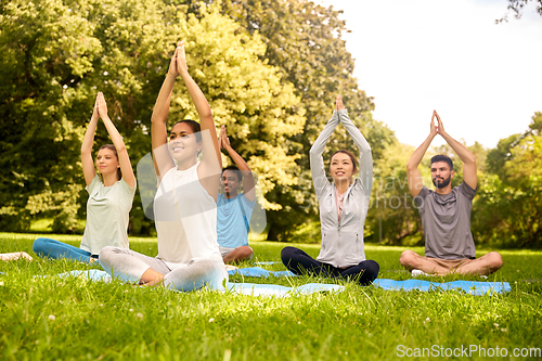 Image of group of people doing yoga at summer park