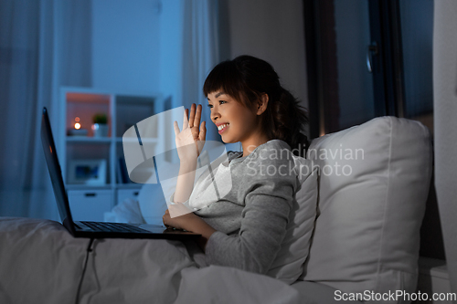 Image of woman having video call on laptop in bed at night