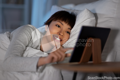 Image of asian woman with tablet pc in bed at home at night