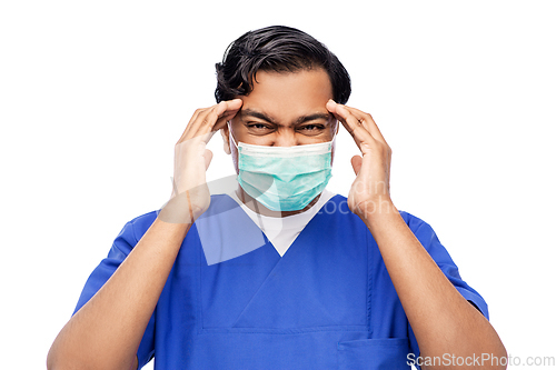 Image of stressed indian doctor in mask having headache