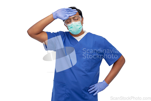 Image of tired indian male doctor in blue uniform and mask