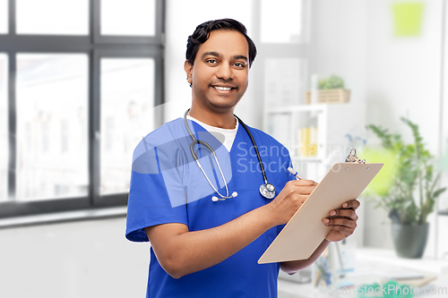 Image of male doctor writing medical report on clipboard