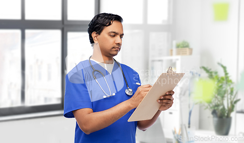 Image of male doctor writing medical report on clipboard