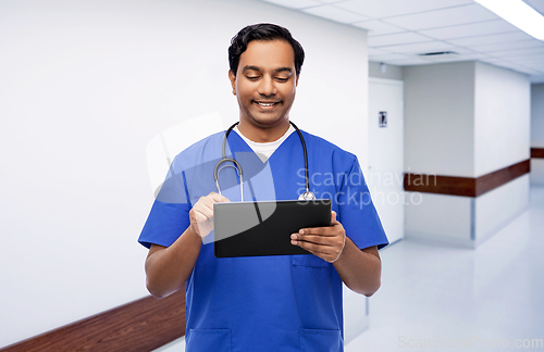 Image of smiling doctor or male nurse using tablet computer