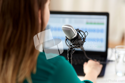 Image of woman with microphone recording podcast at studio