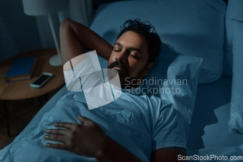 Image of indian man sleeping in bed at home at night