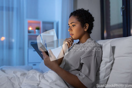 Image of woman with tablet pc in bed at home at night