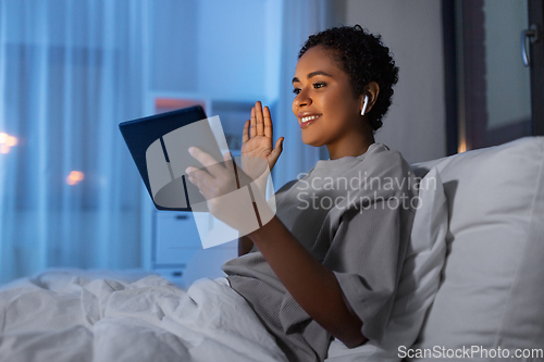 Image of woman with tablet pc in bed having video call