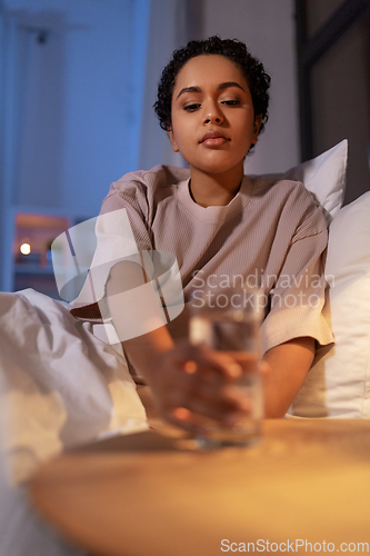 Image of african american woman drinking water at night