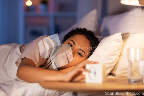 Image of woman awaking because of alarm clock at night