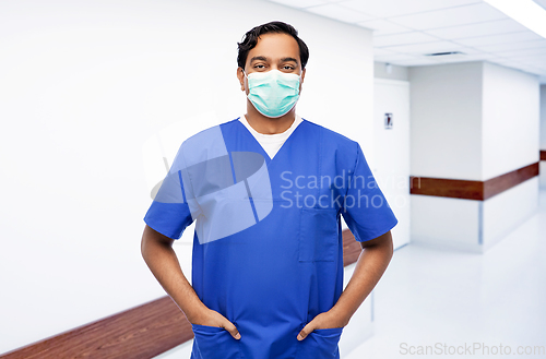 Image of indian male doctor in blue uniform and mask