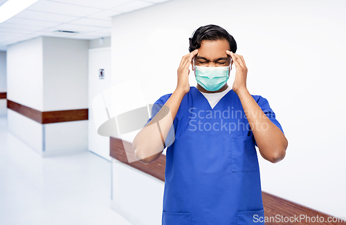 Image of stressed indian doctor in mask having headache