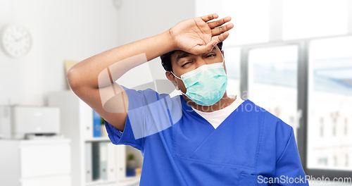 Image of tired indian male doctor in blue uniform and mask