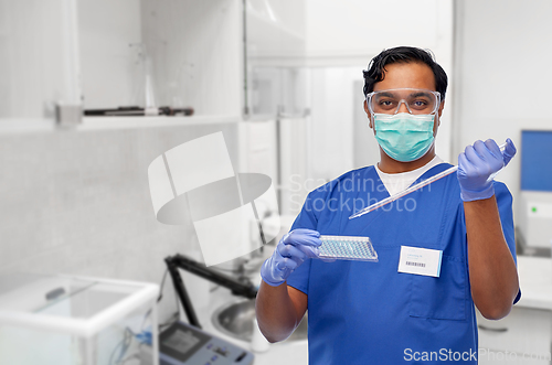 Image of indian scientist in mask with dropper and vaccine