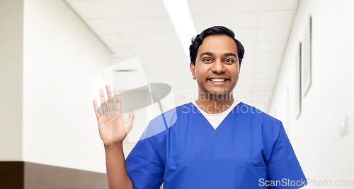 Image of happy indian doctor or male nurse waving hand