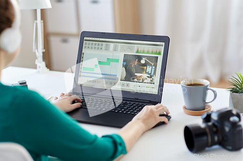 Image of woman with video editor program on laptop at home