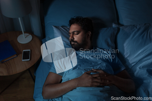 Image of indian man sleeping in bed at home at night