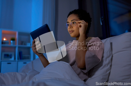 Image of woman with tablet pc in bed at home at night