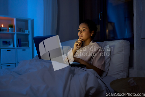 Image of woman with laptop in bed at home at night