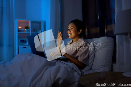 Image of woman having video call on laptop in bed at night