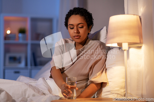 Image of african american woman drinking water at night