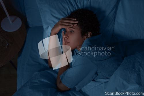 Image of sleepless african woman lying in bed at night