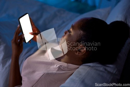 Image of woman with smartphone in bed at home at night