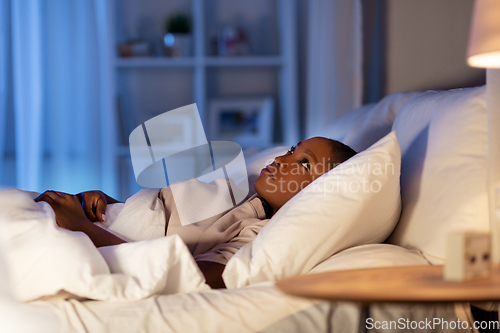 Image of sleepless african woman lying in bed at night