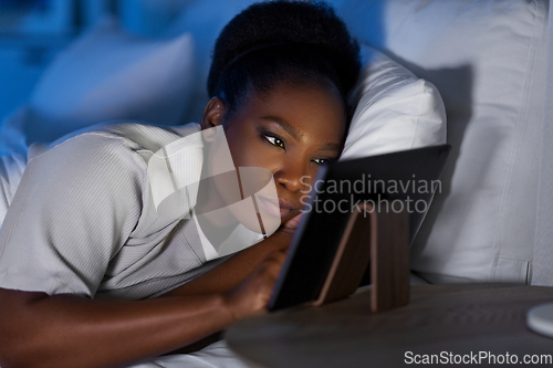 Image of woman with tablet pc in bed at home at night