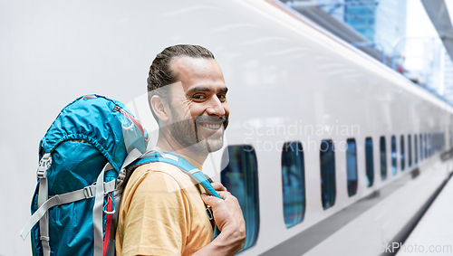 Image of smiling man with backpack traveling over train