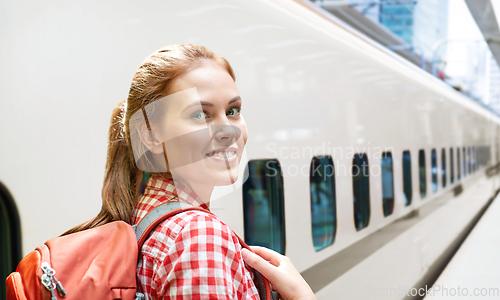 Image of smiling woman with backpack traveling over train