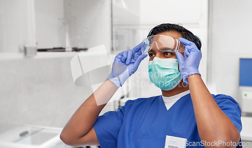 Image of indian male doctor in blue uniform and mask