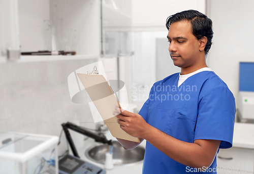 Image of male doctor writing medical report on clipboard