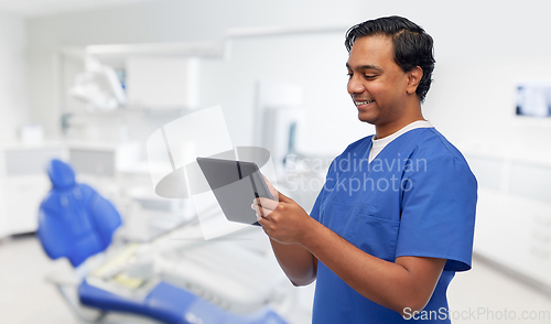 Image of happy doctor or male dentist using tablet computer