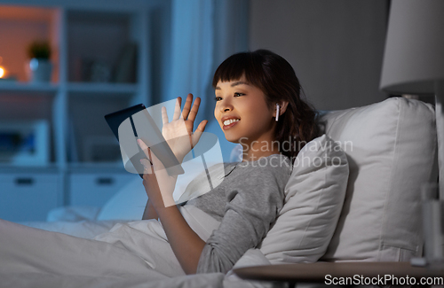 Image of woman with tablet pc in bed has video call