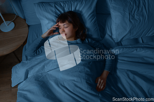 Image of asian woman sleeping in bed at home at night