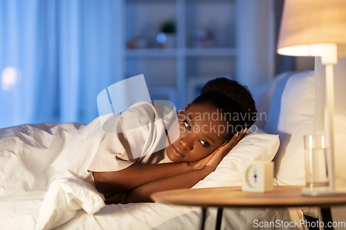 Image of sleepless african woman lying in bed at night