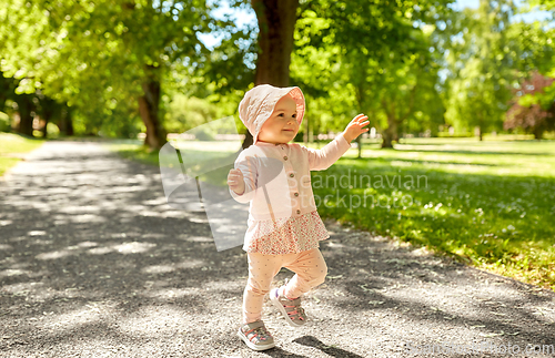 Image of happy little baby girl walking in summer park